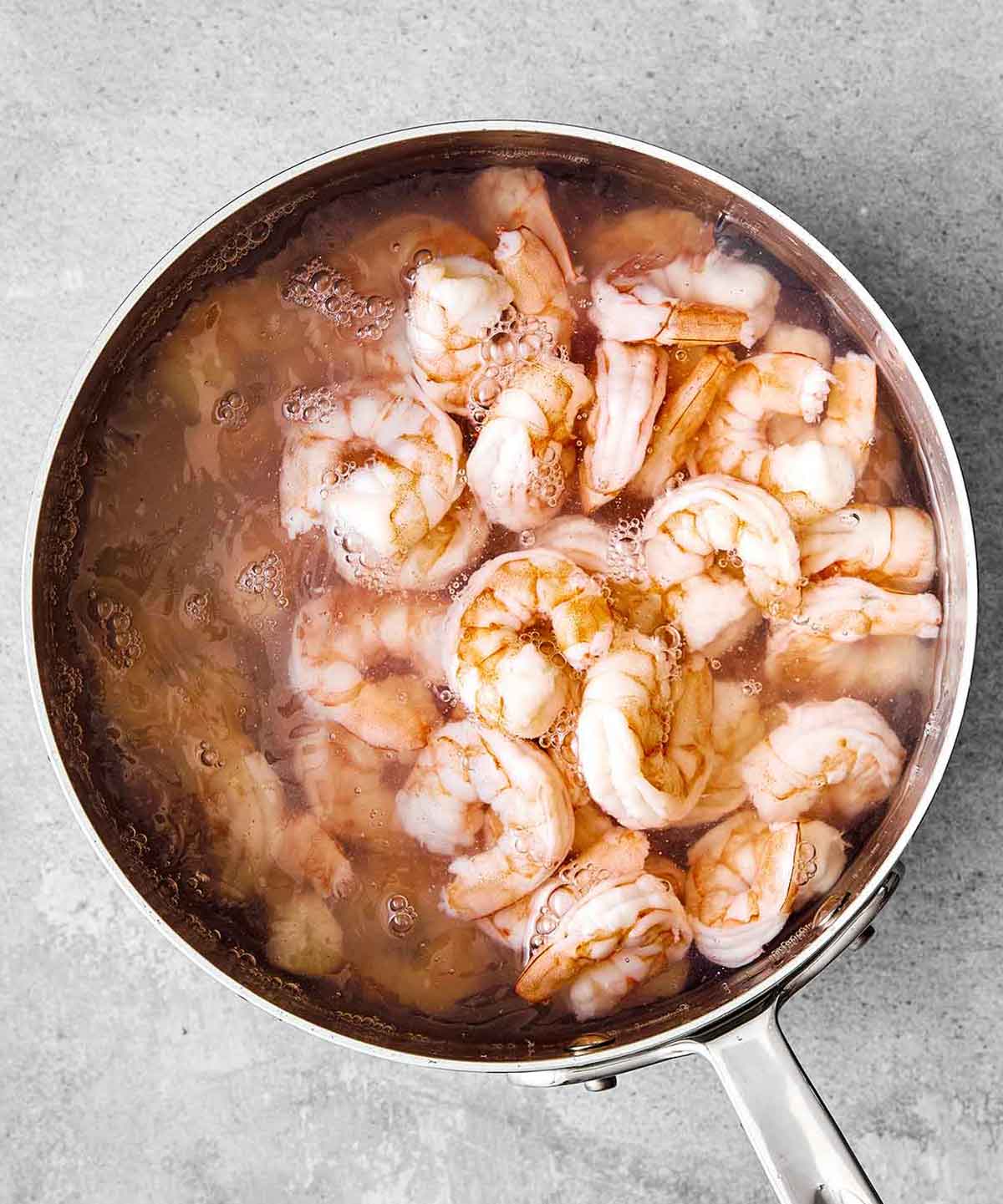 This cold shrimp salad is the ultimate summer salad! Chilled shrimp are tossed with crisp celery and red onion, then coated in a bright, creamy dressing. Boiling shrimp in a pot.