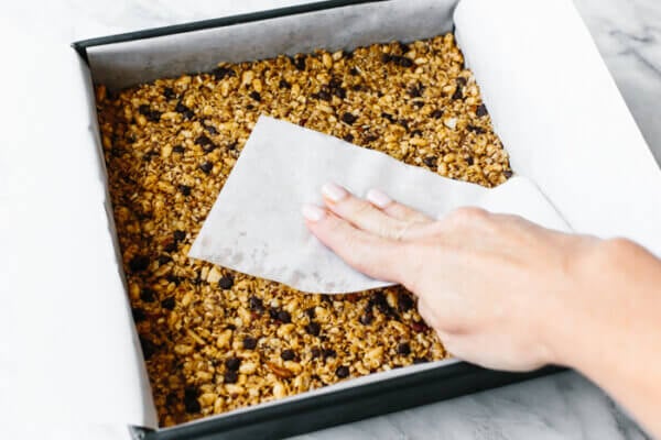 A pan with parchment paper and granola bar mixture