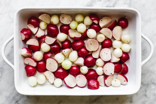 Cut radishes and onions in a baking dish for roasted radish salad