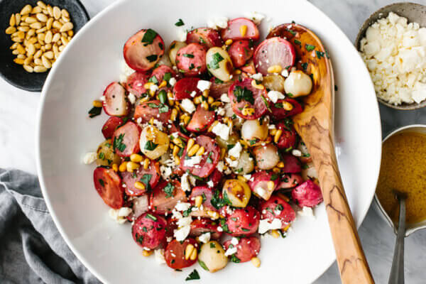 A large bowl of roasted radish salad with a wooden spoon