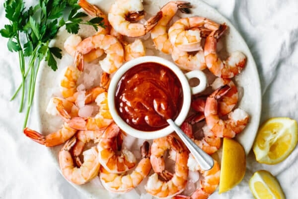 Shrimp cocktail on a platter next to lemon wedges