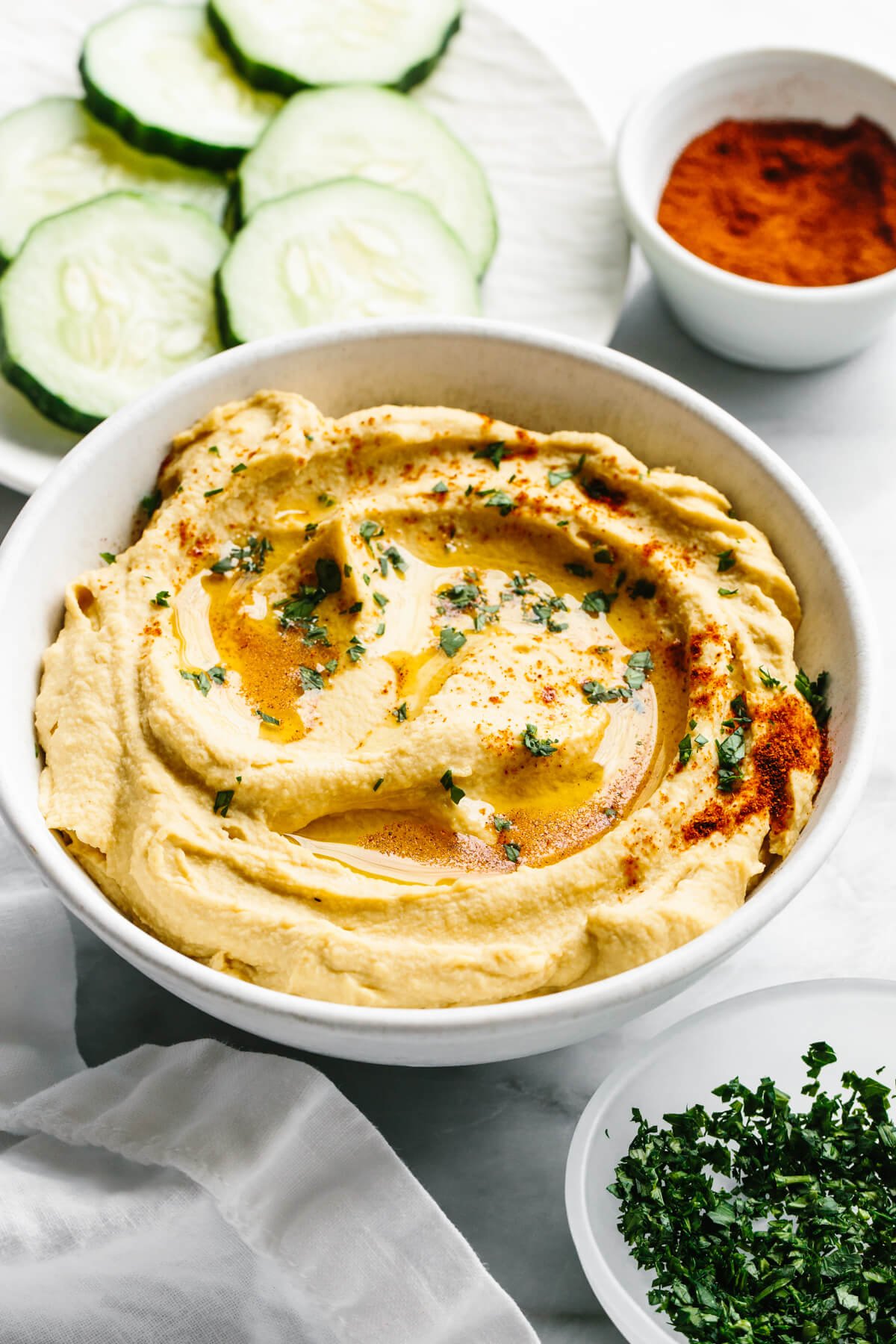 This really is the best hummus recipe! It’s a classic hummus that's creamy, savory, done in under 3 minutes with a blender. A bowl of hummus next to paprika