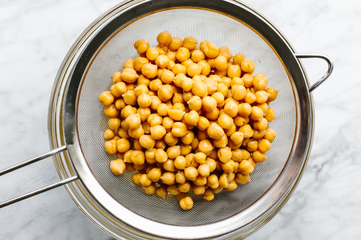 This really is the best hummus recipe! It’s a classic hummus that's creamy, savory, done in under 3 minutes with a blender. Washing chickpeas in a sieve for hummus