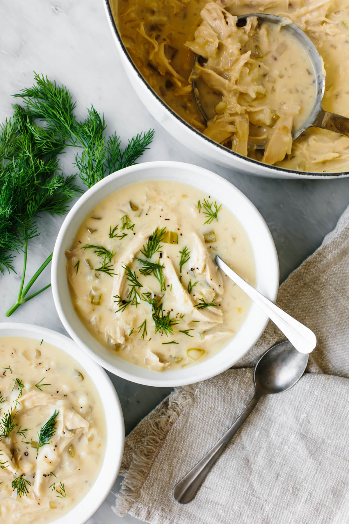 If you love a good chicken and rice combo, this Greek Avgolemono soup is the most comforting, delicious, and easy way to make it! Bowls and a pot of Avgolemono soup