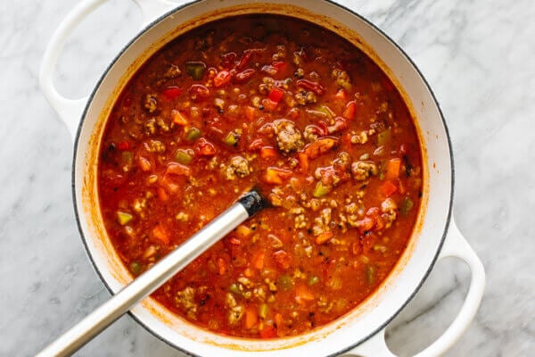 A pot cooking stuffed pepper soup with a spoon