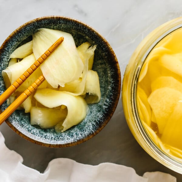 A jar of quick pickled ginger next to chopsticks