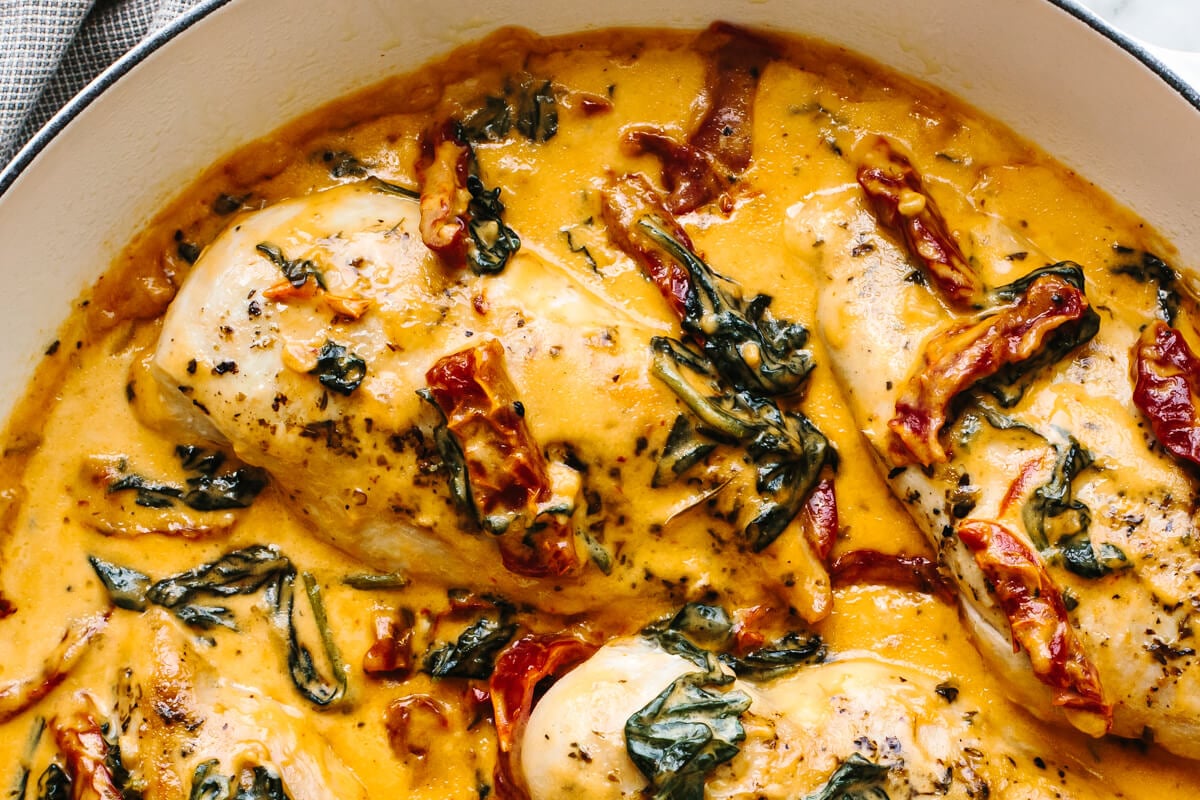 Steal hearts with this creamy tuscan chicken recipe! Seared Italian chicken simmers in a rich and creamy, spinach and sun-dried tomato sauce. A close of up a skillet with creamy tuscan chicken