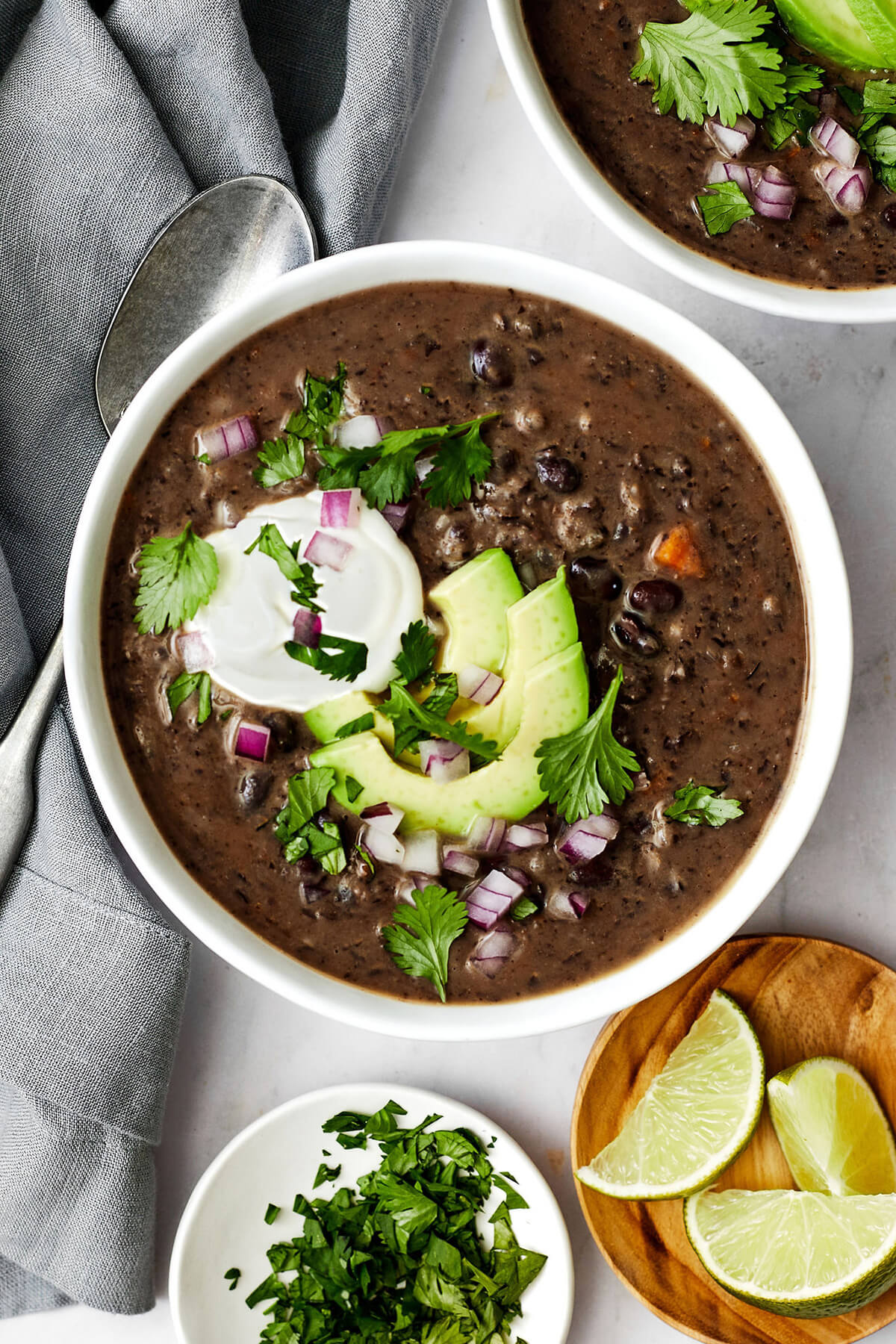 Don't look past this easy black bean soup recipe! It's a delicious vegetarian meal that's filling and layered with savory and spiced flavors. Black bean soup in a bowl next to a napkin