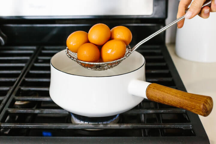 Placing eggs into a pot to boil