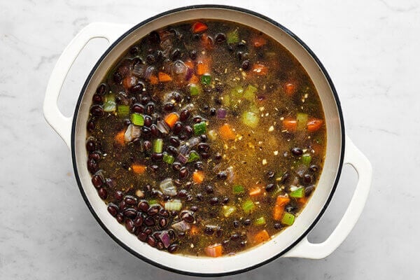 Cooking a black bean soup in a white pot
