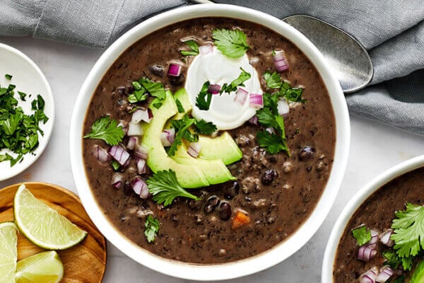 A bowl of black bean soup topped with avocado and sour cream