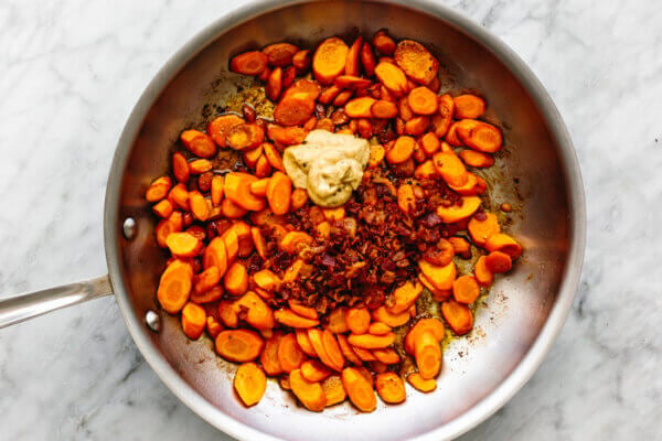 Tossing sauteed carrots with a bacon Dijon dressing