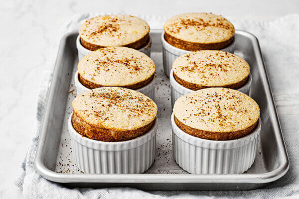 A baking sheet with spiced pear souffles in ramekins
