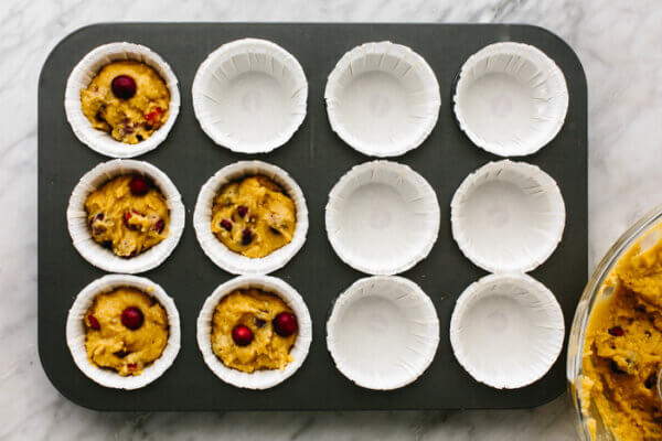 A tray with uncooked cranberry orange muffins