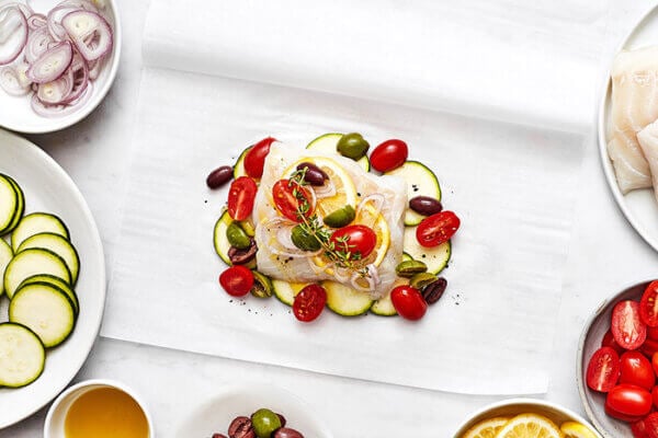 Adding fish en papillote layers on parchment paper