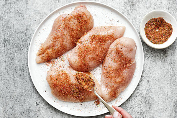 Seasoning chicken breasts on a plate