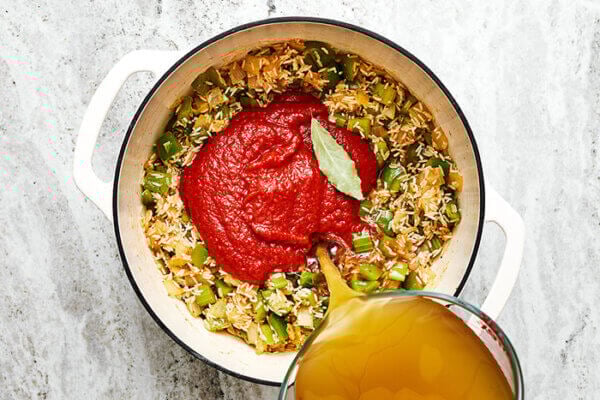 Mixing broth in a pot for jambalaya