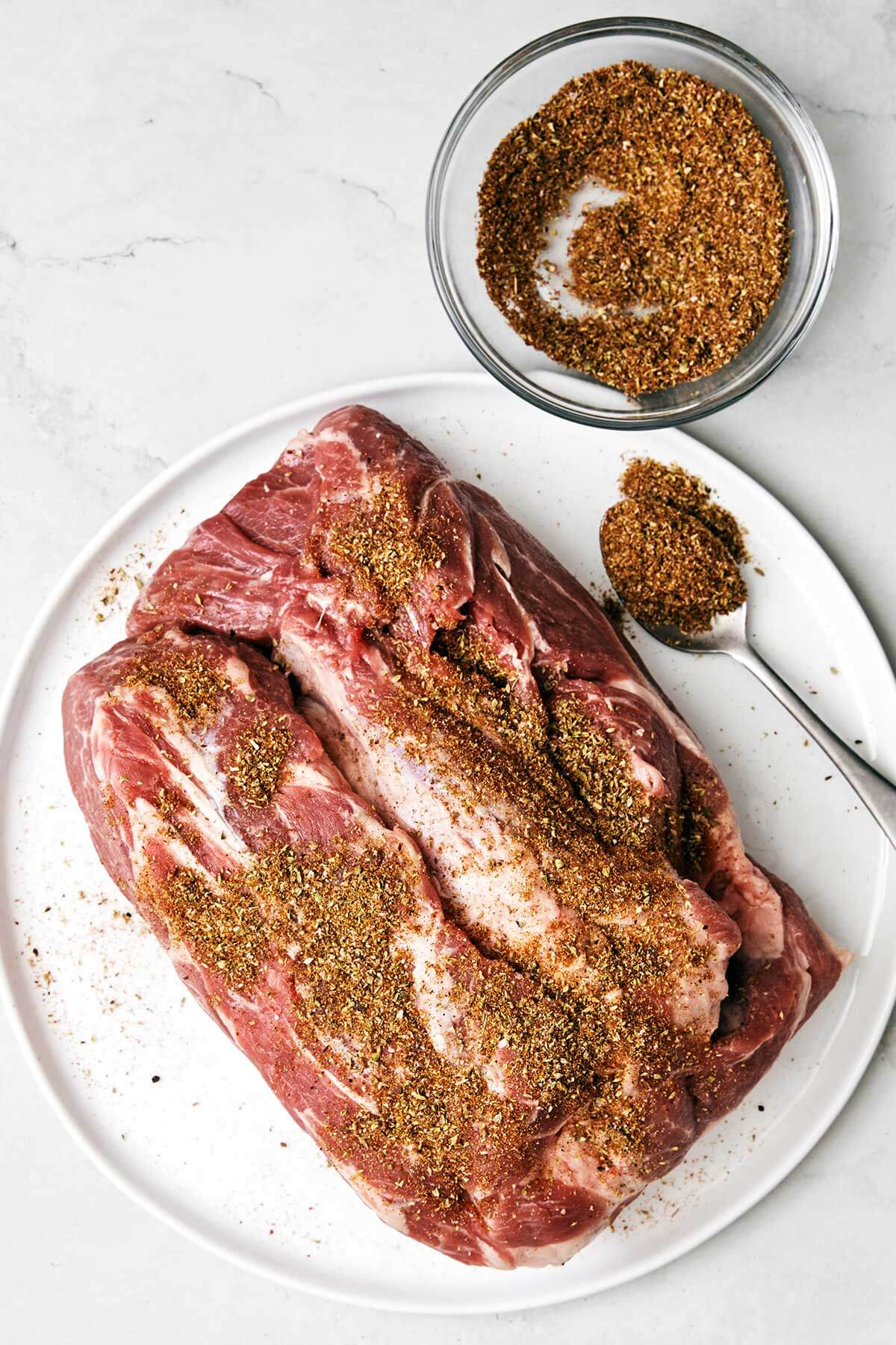 The best Mexican carnitas recipe that's juicy, full of flavor, fall-apart tender, and super easy to make in a slower cooker! Adding seasoning to a pork shoulder.