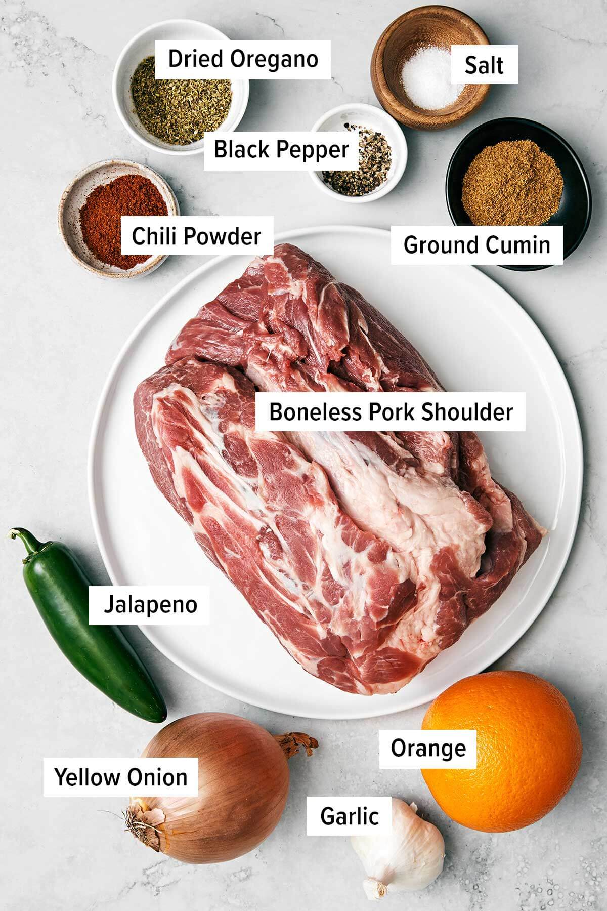 The best Mexican carnitas recipe that's juicy, full of flavor, fall-apart tender, and super easy to make in a slower cooker! Ingredients for carnitas on a table.