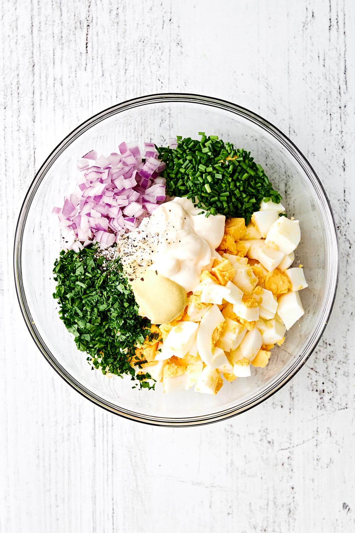 This is the classic deli-style egg salad we all know and love—perfectly creamy, delightfully chunky, and filled with fresh flavors. Egg salad ingredients in a bowl.