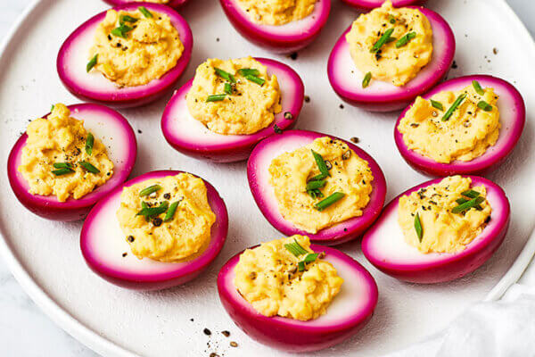 A white platter of beet pickled deviled eggs