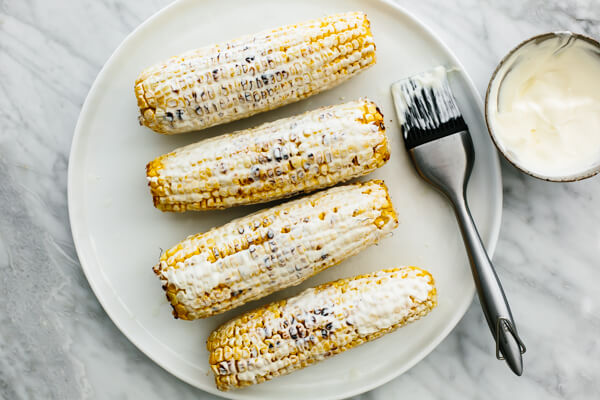 Slathering mayo on elote