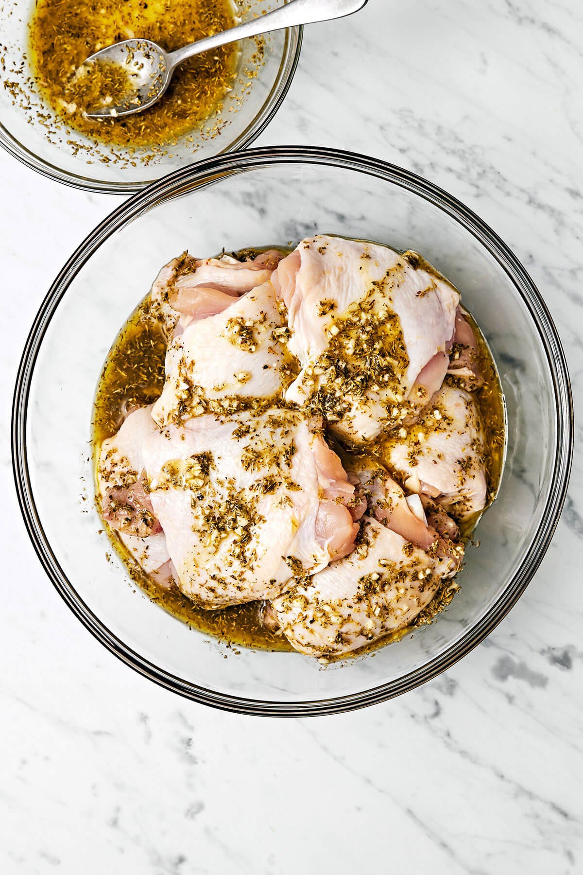 This Greek lemon chicken is the best dinner with juicy, tender, and crisp chicken thighs baked coated in a delicious lemon-herb marinade. Marinating Greek lemon chicken in a bowl