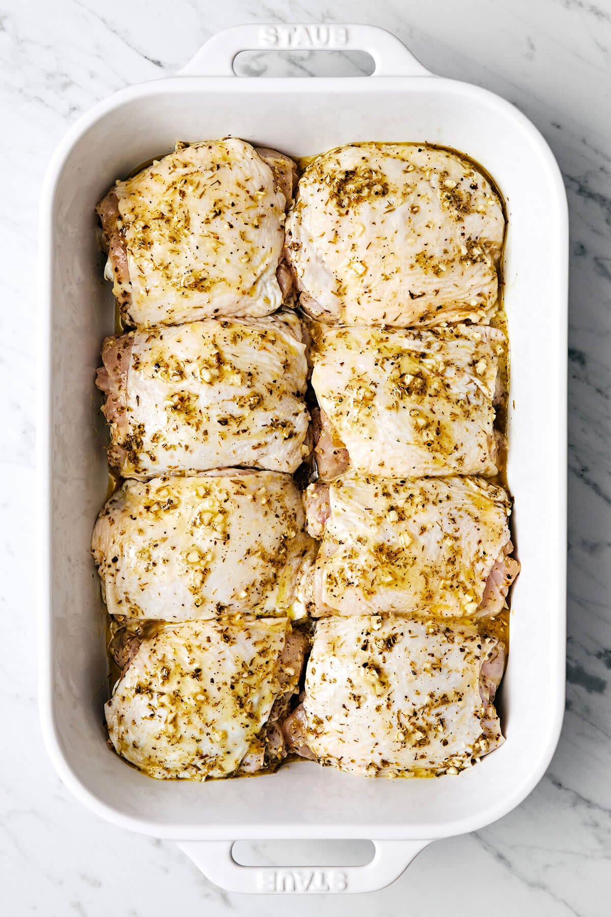 This Greek lemon chicken is the best dinner with juicy, tender, and crisp chicken thighs baked coated in a delicious lemon-herb marinade. Greek lemon chicken in a white baking dish
