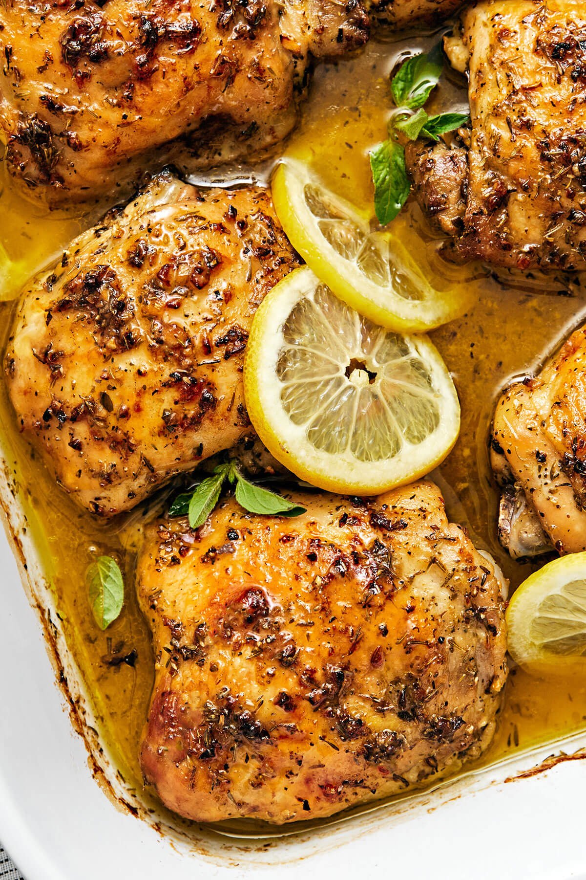 This Greek lemon chicken is the best dinner with juicy, tender, and crisp chicken thighs baked coated in a delicious lemon-herb marinade. A close up of Greek lemon chicken