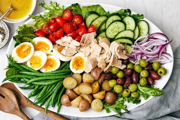 A white platter of Nicoise salad