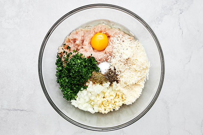 Mixing chicken meatball ingredients in a bowl