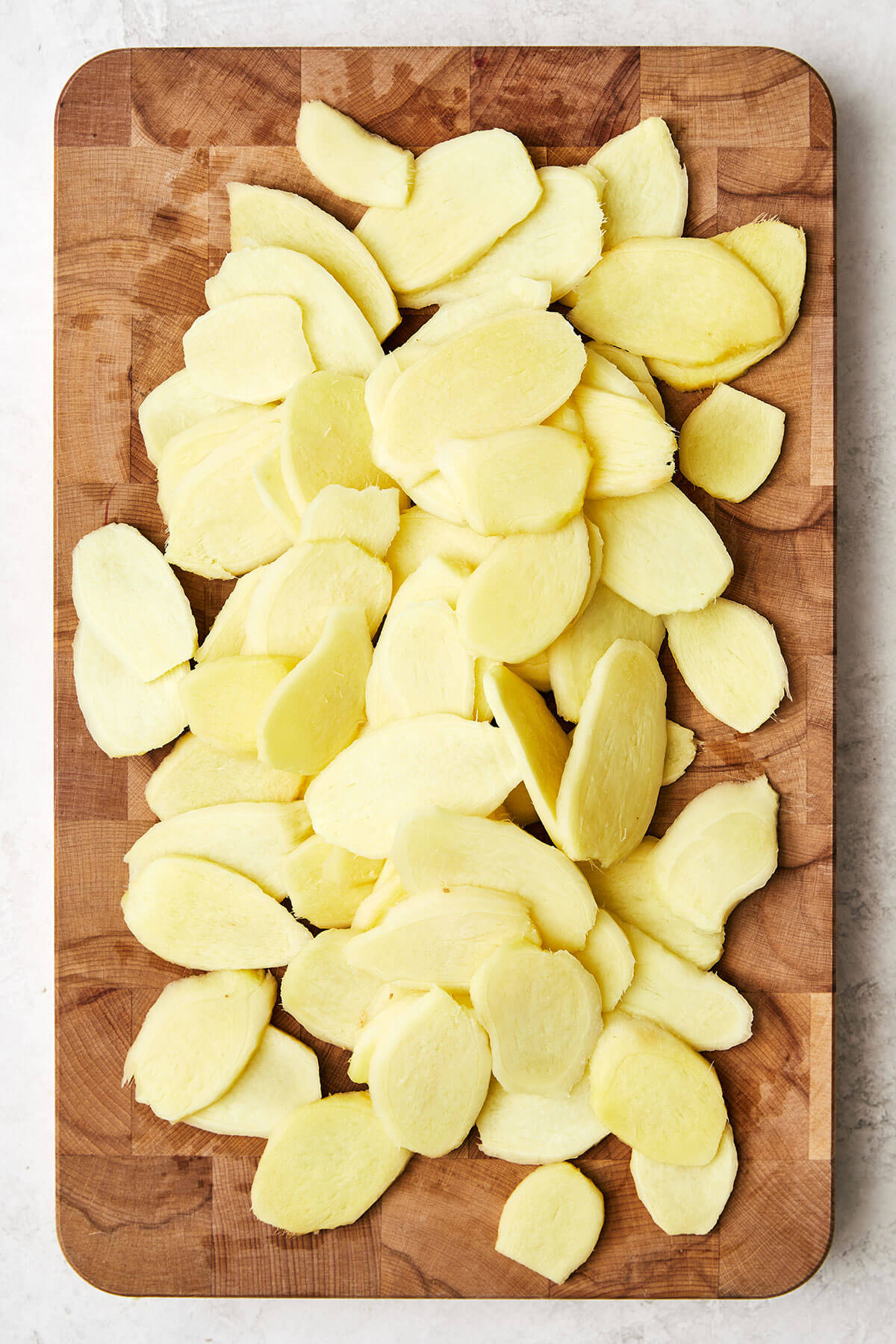 This easy homemade candied ginger is a tasty way to enjoy ginger while reaping all its shining health benefits! Sliced ginger on a wooden board
