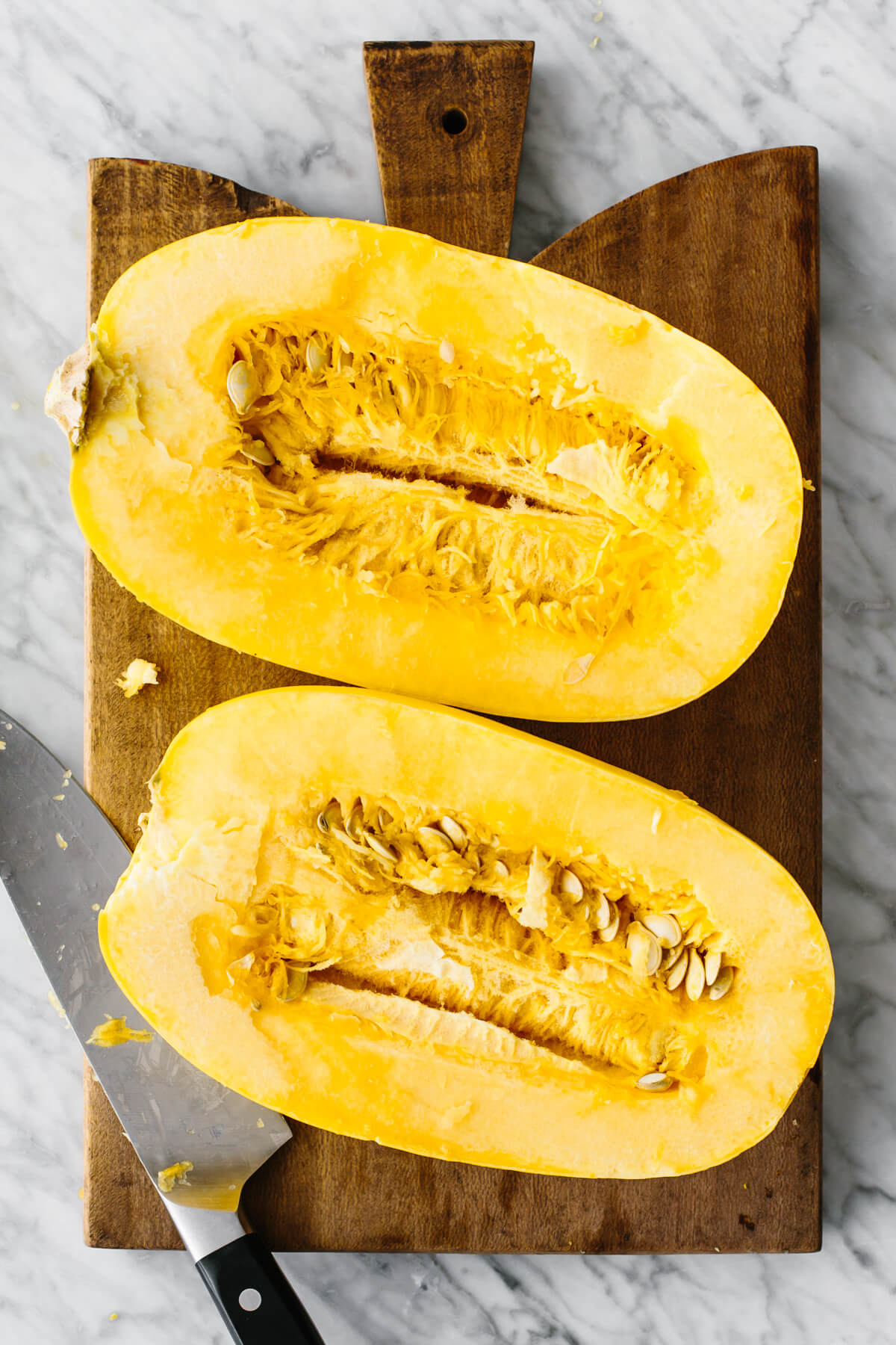 A spaghetti squash cut in half on a cutting board.