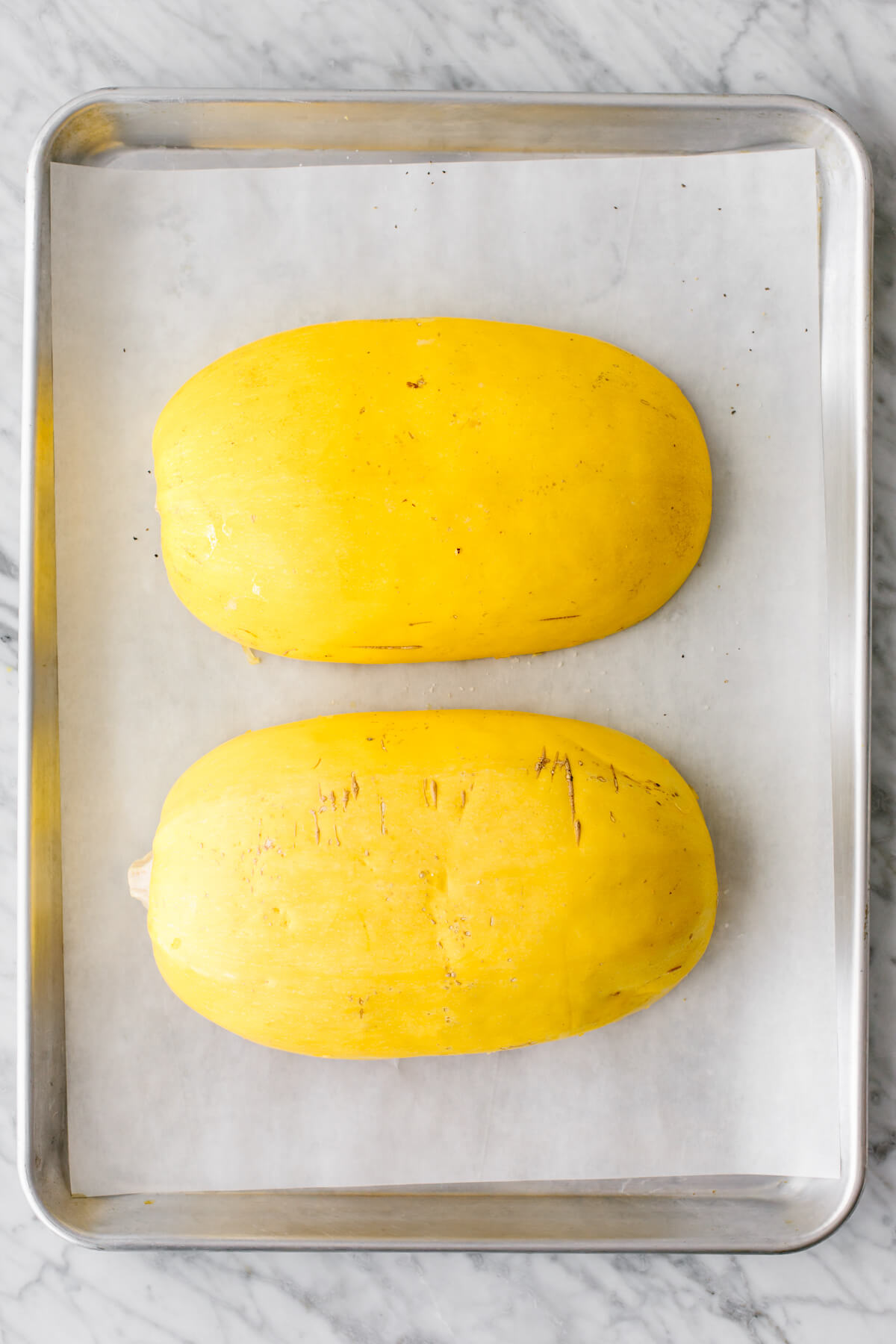 A spaghetti squash cut in half on a baking sheet.