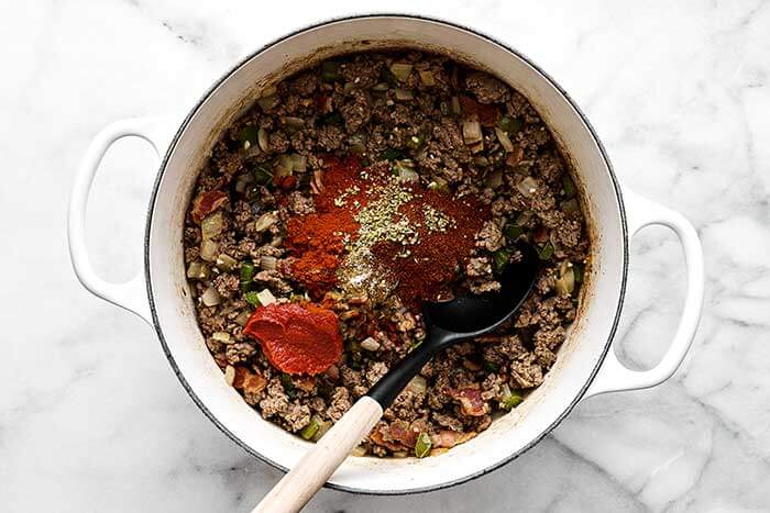 Adding aromatics to chili.