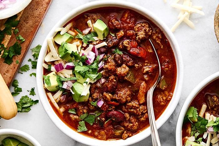 A bowl of chili with toppings.
