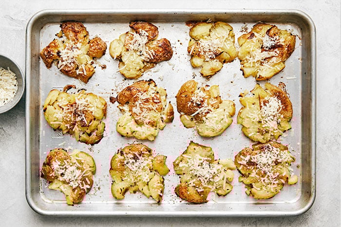 A baking sheet with smashed potatoes and cheese