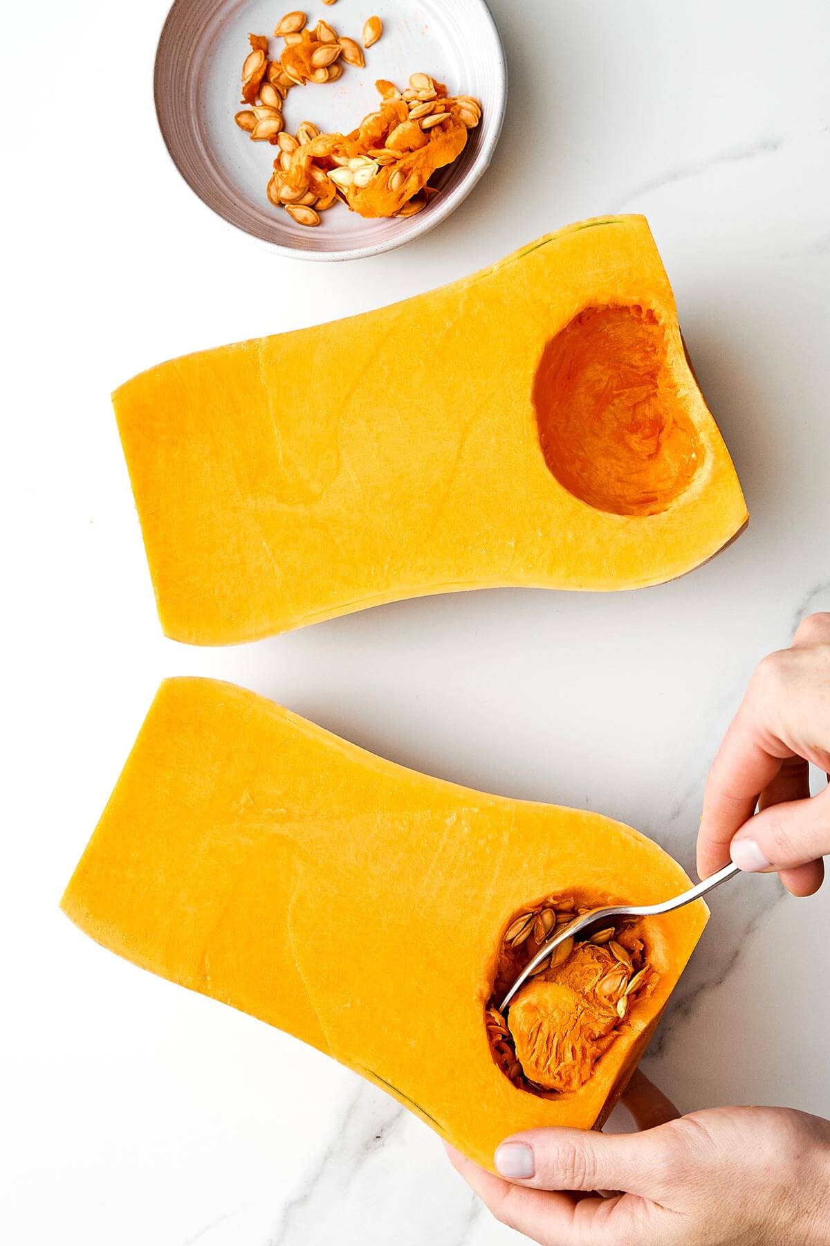 Scooping seeds out of butternut squash.