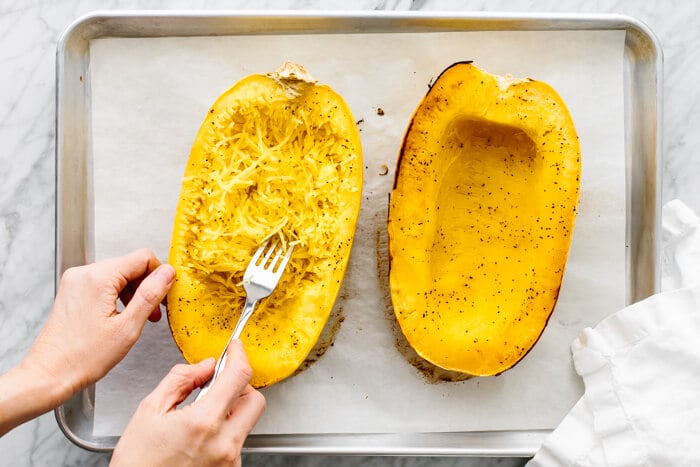 Scraping the inside flesh of a spaghetti squash.