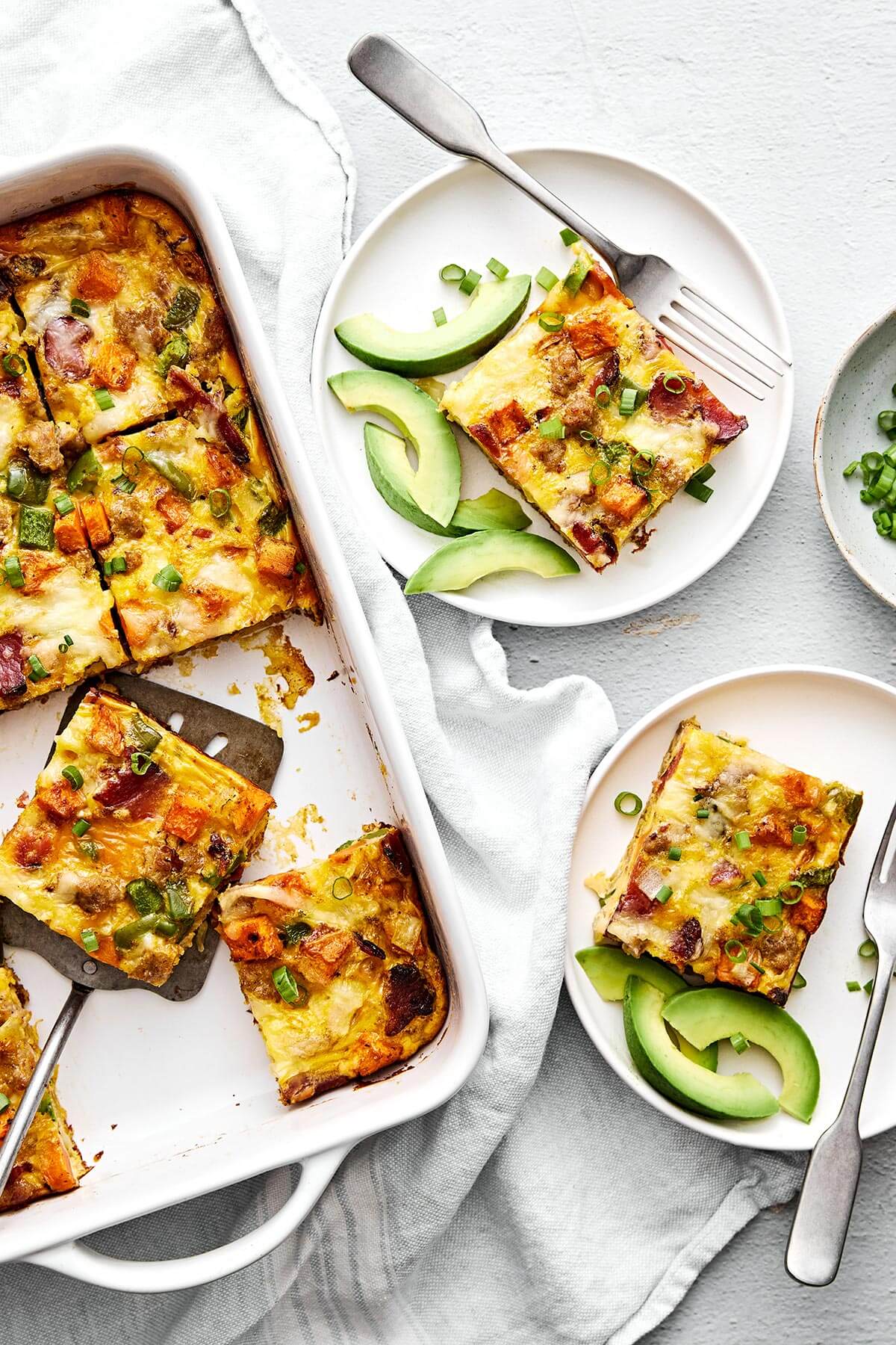 This is the best breakfast casserole loaded with bacon, sausage, sweet potatoes, and plenty of veggies. Plus, it's always a crowd favorite! Slices of breakfast casserole on plates.
