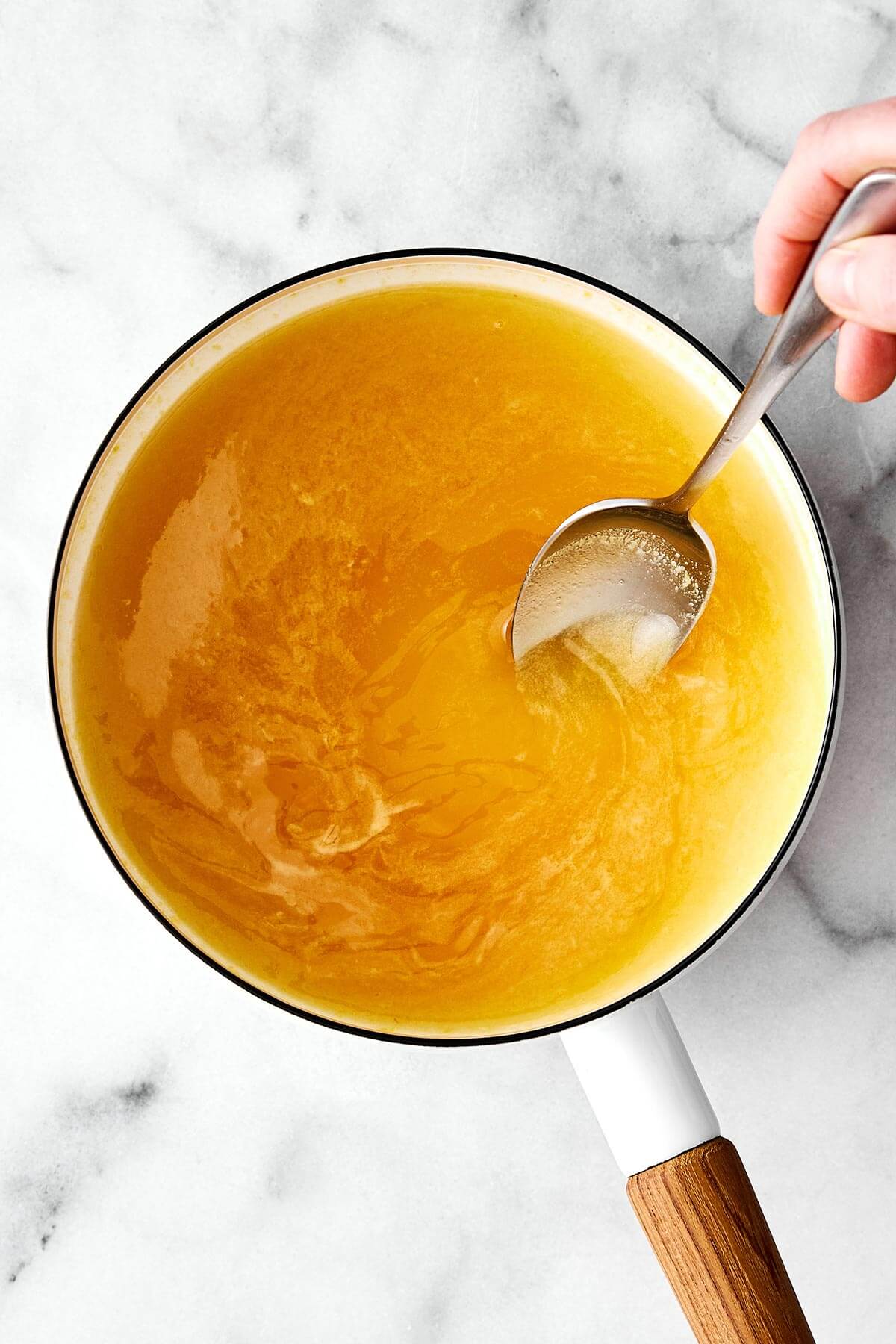 Mixing orange juice and honey in a pot.