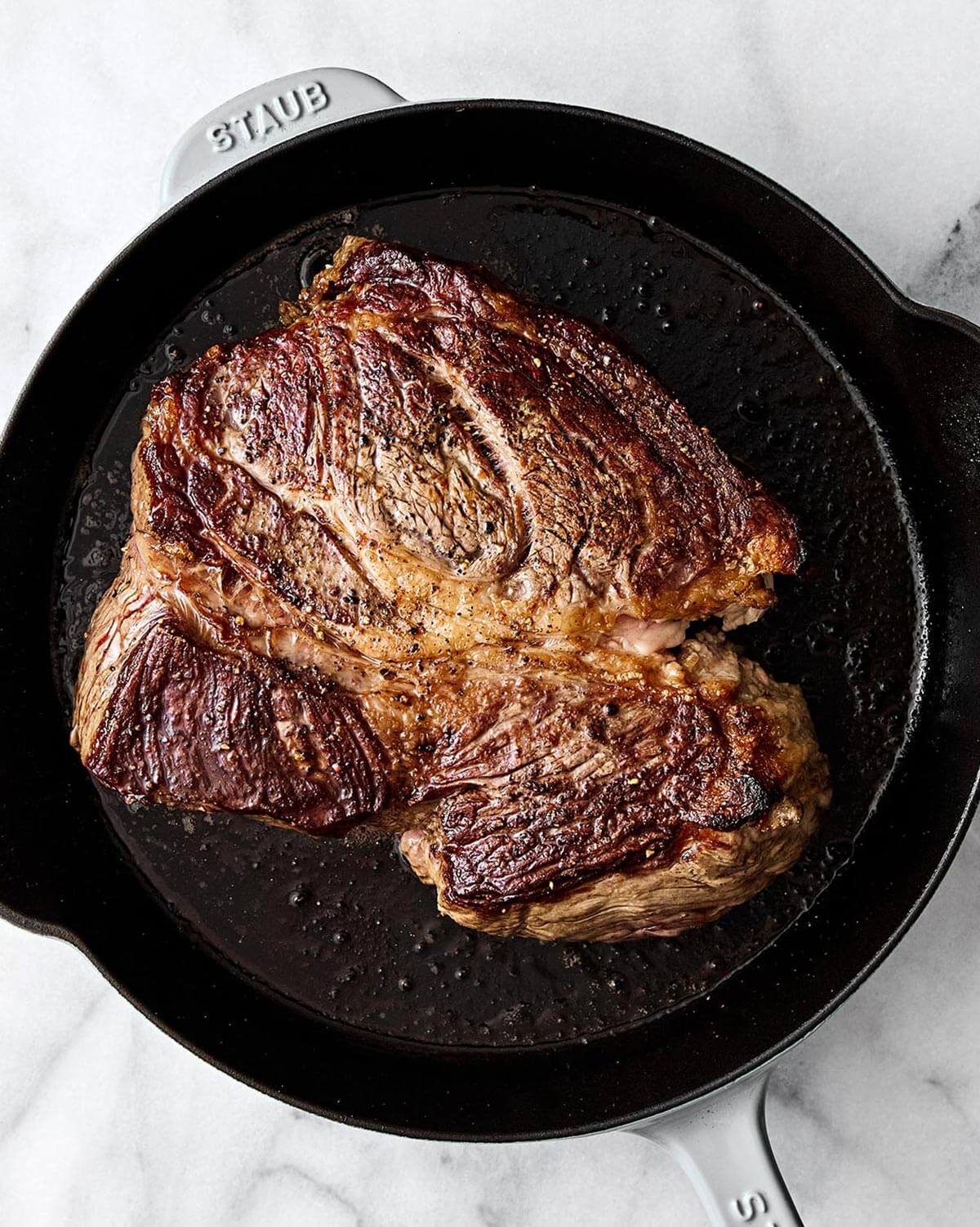 Searing chuck roast in a pan for pot roast.