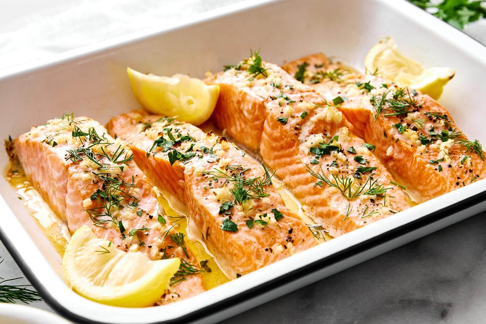 A white tray of lemon garlic baked salmon.