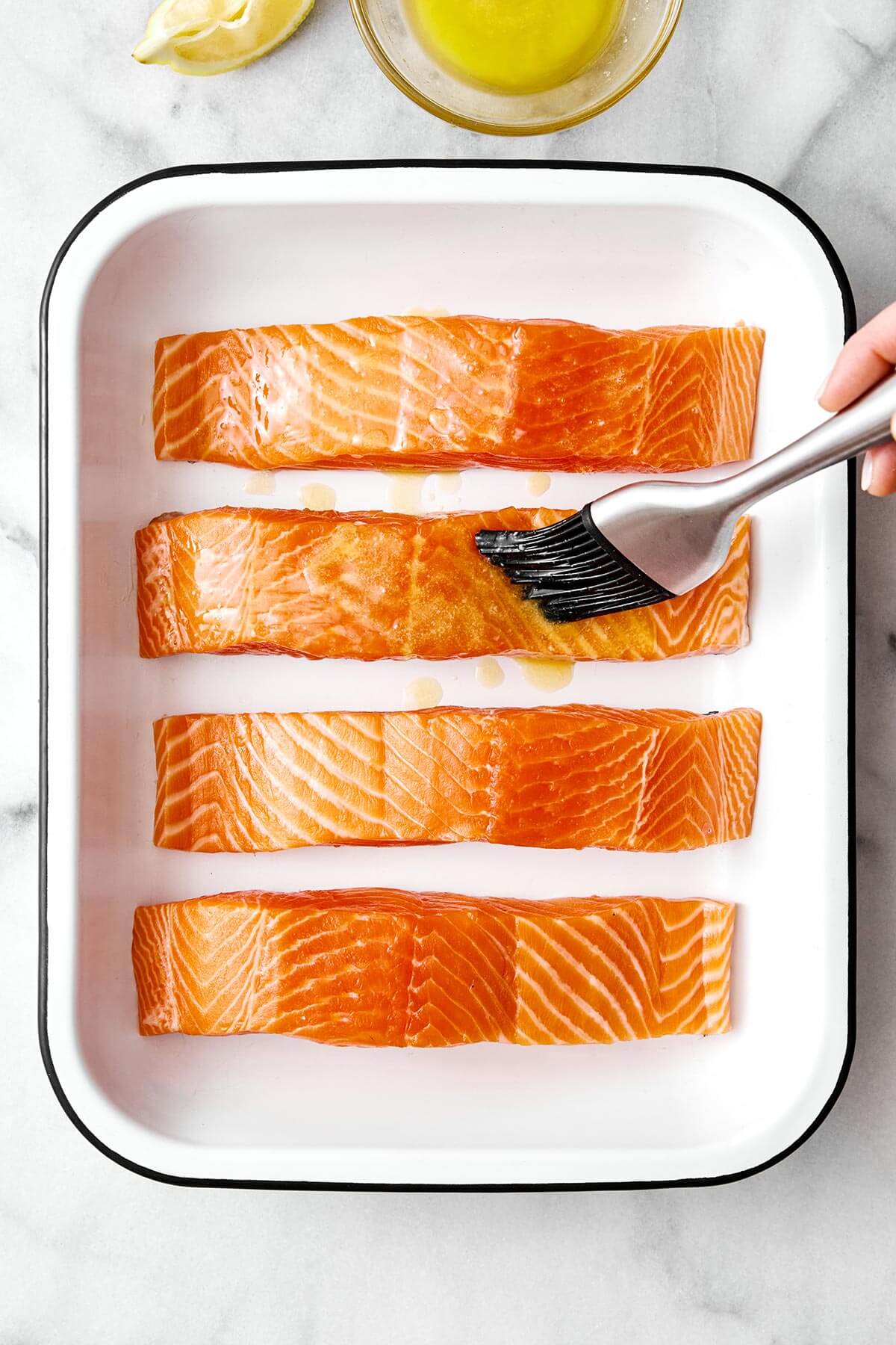 Brushing butter on salmon fillets.