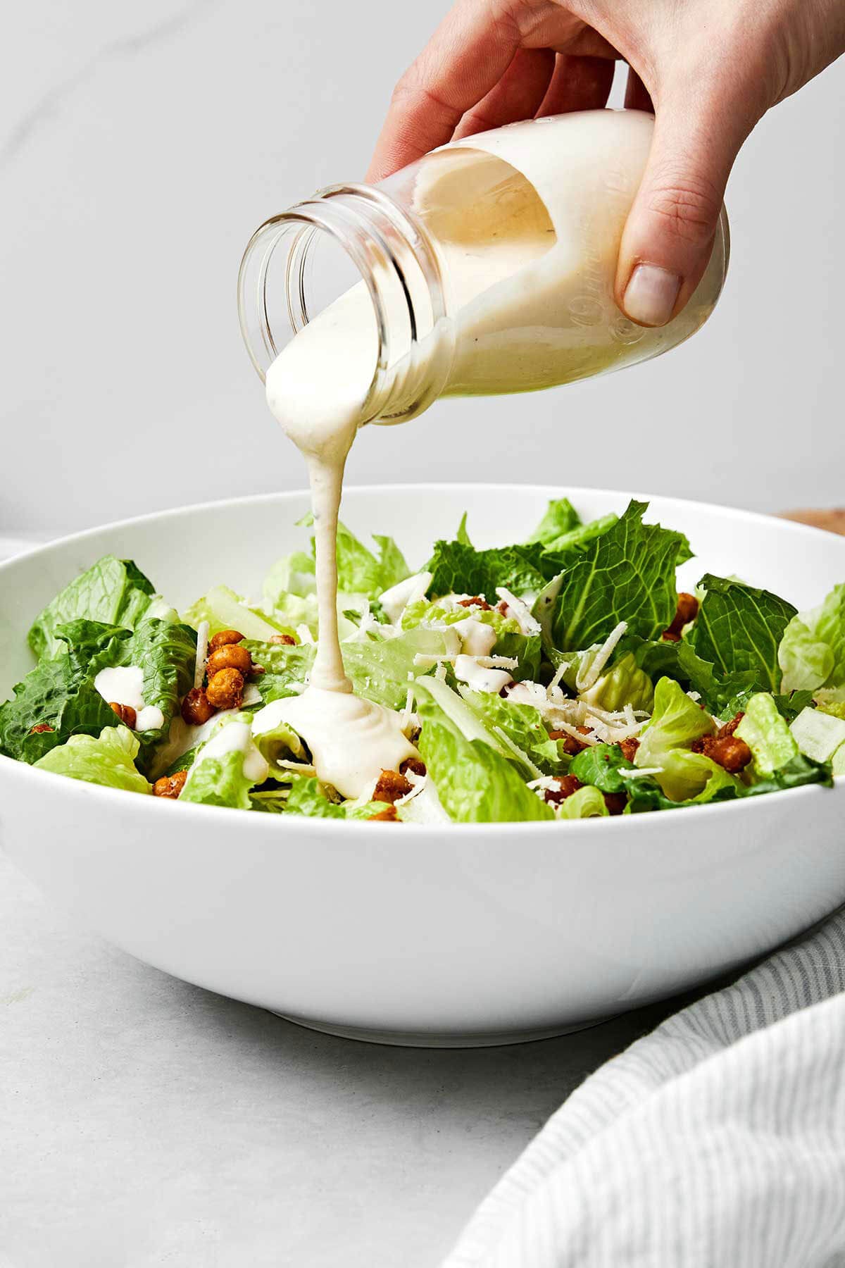 Pouring Caesar dressing over salad.