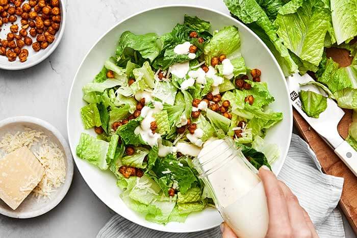 Adding dressing to Caesar salad.
