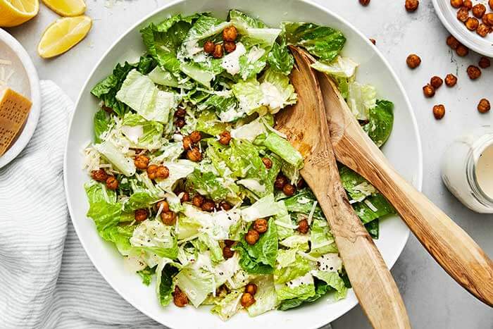 Caesar salad with serving spoons.