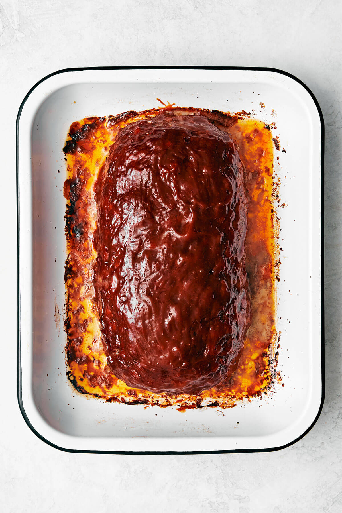 Here's my secret to the best classic meatloaf recipe! It's tender and moist, layered with flavor, and brushed with a tasty meatloaf sauce! Cooked meatloaf in a pan.