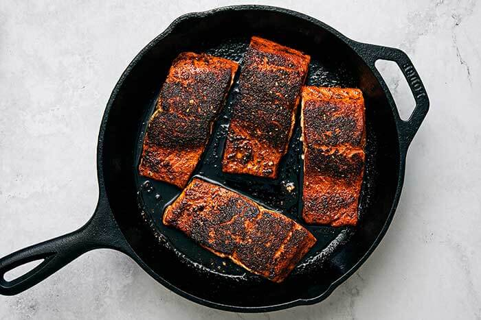 Cooking blackened salmon in a cast iron pan.