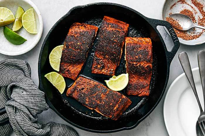 Blackened salmon filets in a cast iron pan.
